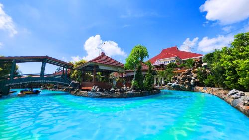 a swimming pool at a resort with a bridge at Griya Yodesiya Resort Semarang in Karangjati