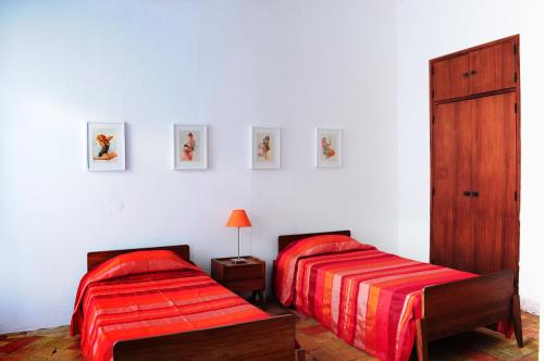 two beds in a white room with red sheets at Casa da Avó Nina in Fuzeta