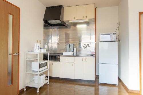 a kitchen with white cabinets and a white refrigerator at Nagano Station Inn East in Nagano