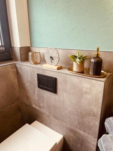 a clock on a shelf above a toilet in a bathroom at Moderne Ferienwohnung ab März 2026 mit Saunabereich in Buchet