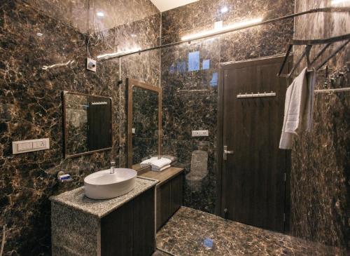 a black marble bathroom with a sink and a mirror at Serenity Hill Resort Near 2Km Fateh Sagar Lake Udaipur in Udaipur
