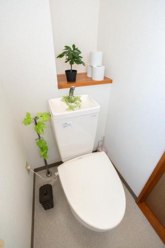 a bathroom with a toilet with two plants on it at Nagano Station Inn East in Nagano