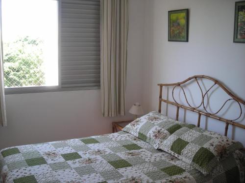 Una cama con edredón en un dormitorio en Condominio Edifício Las Vegas, en Guarujá