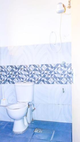 a bathroom with a toilet and blue and white tiles at Tum Hotel & Conferencing in Mombasa