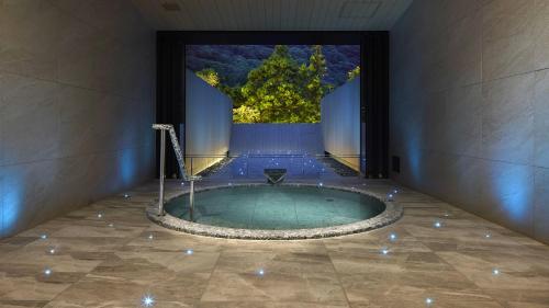 a jacuzzi tub in a room with a tree at Hatsuhana in Hakone