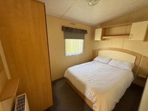 a small bedroom with a bed and a window at Sunnymede i15 Hot Tub - pet friendly, bed linen - Meadow Lakes Caravan & Lodge Hire in Ingoldmells