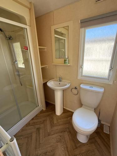 a bathroom with a toilet and a sink and a shower at Sunnymede i15 Hot Tub - pet friendly, bed linen - Meadow Lakes Caravan & Lodge Hire in Ingoldmells