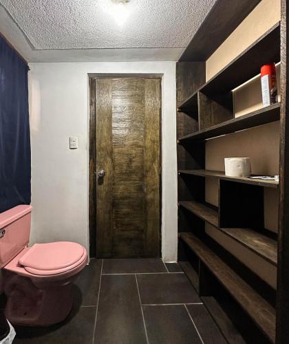 a bathroom with a pink toilet and a wooden door at Hospedajes Alta Terra in Quetzaltenango