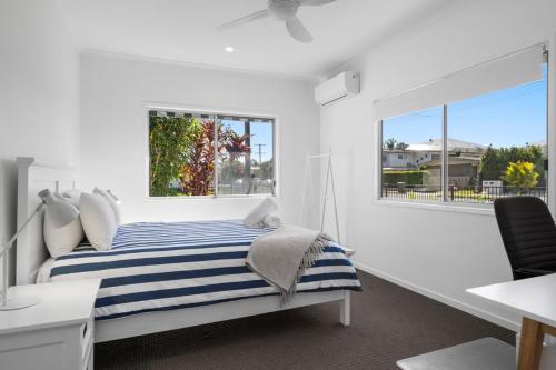 a white bedroom with a blue and white striped bed at 1 Seaspray Avenue in Coolum Beach