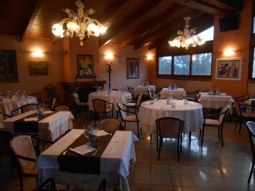 restauracja z białymi stołami, krzesłami i żyrandolami w obiekcie Hotel La Maddalena w mieście Quattro Castella