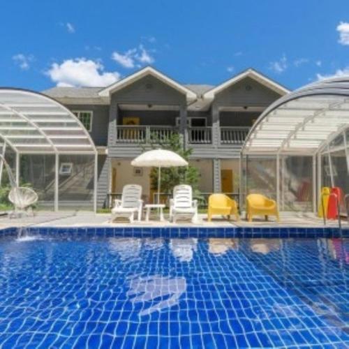 a house with a swimming pool with chairs and an umbrella at Green Soochaehwa Pension Yangyang in Yangyang