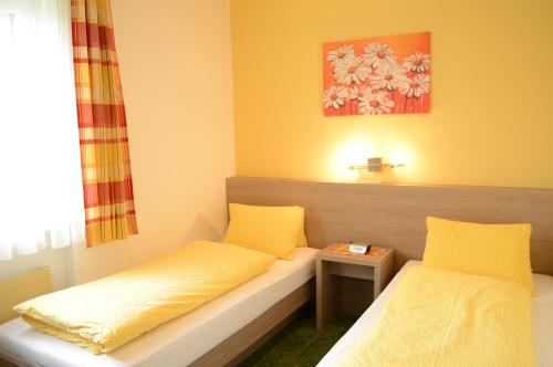 Pokój z 2 łóżkami i żółtymi poduszkami w obiekcie Apartmenthaus Oberlehen w mieście Abtenau