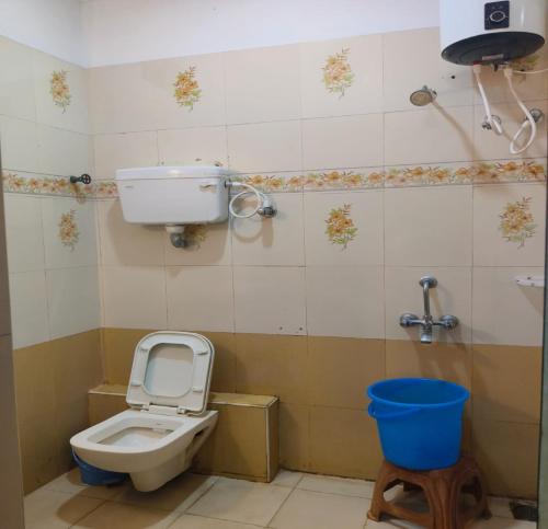 a bathroom with a toilet and a blue bucket at Ajantha Beach Guest House in Pondicherry