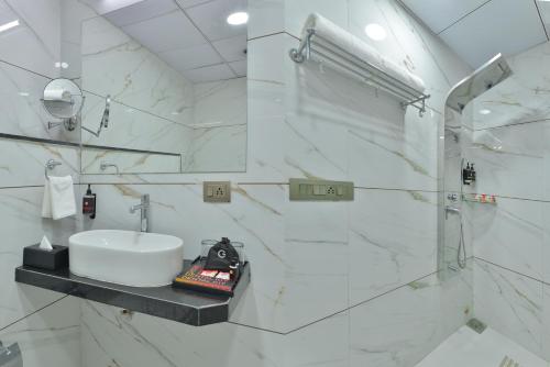 a white bathroom with a sink and a shower at Ginger Kheda, Ahmedabad in Kheda