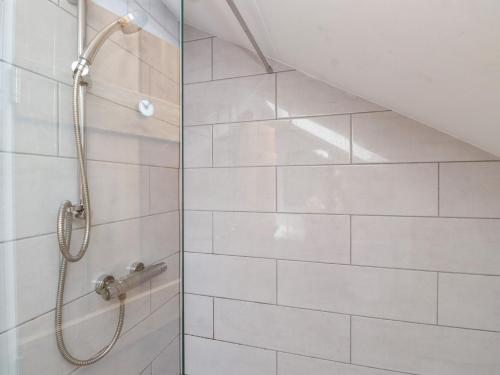 a shower in a bathroom with white tiles at Kiloran in Rhosneigr
