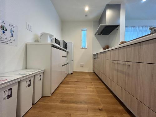 a kitchen with white appliances and a wooden floor at 新築江の電腰越駅前徒歩1分鎌倉江の島観光に最適鎌倉腰越駅前ｂ棟 in Kamakura