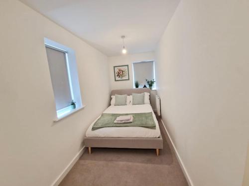 a small bedroom with a bed and two windows at Gatwick Cozy Stopover 4 bedroom house with free Parking in Copthorne