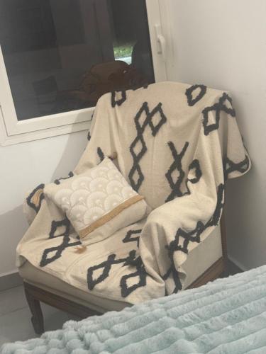 a blanket sitting on a chair next to a bed at Arche du cap de bonne esperance in Sainte-Rose