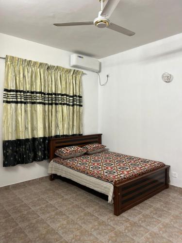 a bedroom with a bed and a window with a curtain at Johasham Villa in Colombo
