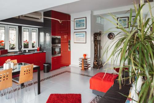 una cocina con armarios rojos, una mesa y una planta en Atico Atalaya, en Alicante