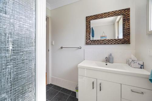 a bathroom with a white sink and a mirror at Seabreeze Cottage in Manyana