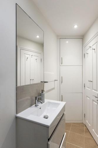 a white bathroom with a sink and a mirror at Flat in Guildford in Stoughton