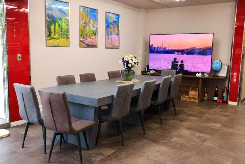 a dining room with a table and chairs and a tv at ゲストハウスシナノスイー Guest House Shinano Swee in Omachi