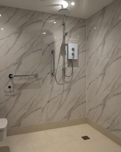 a shower in a bathroom with a marble wall at Croft House in Croyde