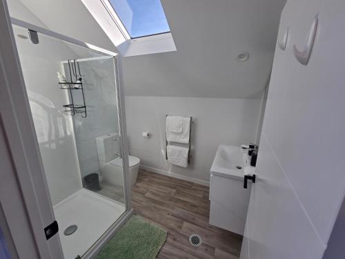 a white bathroom with a shower and a toilet at Great Warm Studio Unit in Queenstown Airport