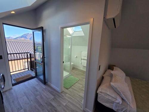a room with a bed and a bathroom with a balcony at Great Warm Studio Unit in Queenstown Airport