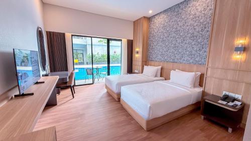 a hotel room with two beds and a television at Savana Hotel & Convention Malang in Malang