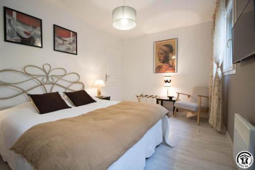 a bedroom with a large white bed and a desk at Villa les paradoux in Pin-Balma