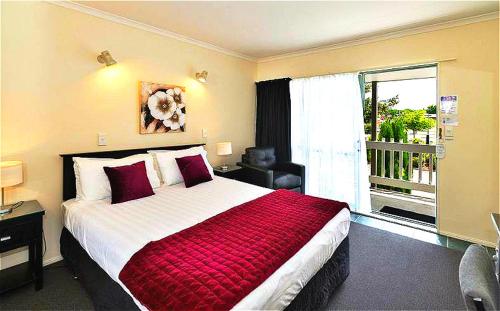 a bedroom with a large bed and a balcony at Accolade Lodge Motel in Rotorua