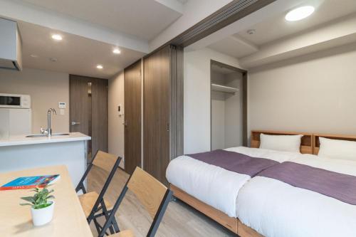 a bedroom with a bed and a table and a kitchen at BON Tokyo Kamata Parkside in Tokyo