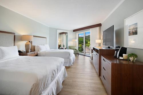 a hotel room with two beds and a flat screen tv at Kauai Beach Resort in Lihue