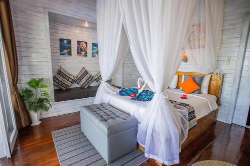 a bedroom with a bed and a couch and curtains at Tatak Bunut Villa Ceningan in Nusa Lembongan