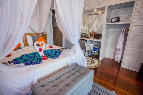 a bedroom with a bed with a couch and a kitchen at Tatak Bunut Villa Ceningan in Nusa Lembongan