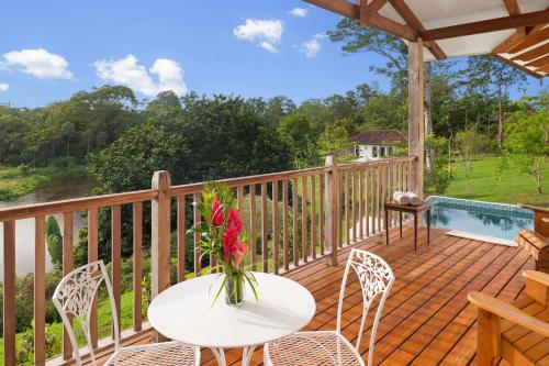 a wooden deck with a table with a vase of flowers at El Lugar Hotel & Nature Reserve Costa Rica in Tigre