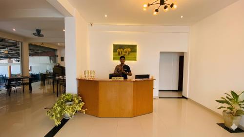a man standing at a reception desk in a lobby at H M C Leisure Villa Devinuwara in Dondra North