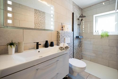 a white bathroom with a sink and a toilet at Apartment Molnar in Žirovnica