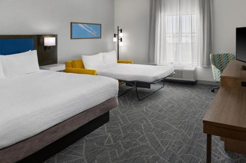 a hotel room with two beds and a couch at Hampton Inn & Suites Syracuse North Airport Area in North Syracuse
