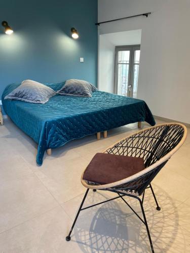 a bed with a blue blanket and a chair in a room at La Secrète in Vogüé