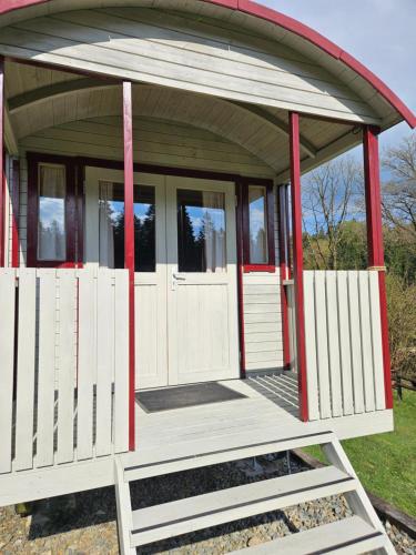 a smallshed with white doors and red poles at Camping La Hêtraie pipowagen in Bullange