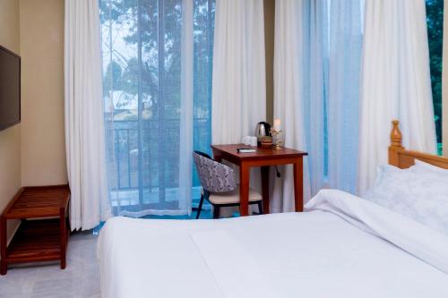 a bedroom with a bed and a desk and a window at Fortis Hill Hotel in Arusha