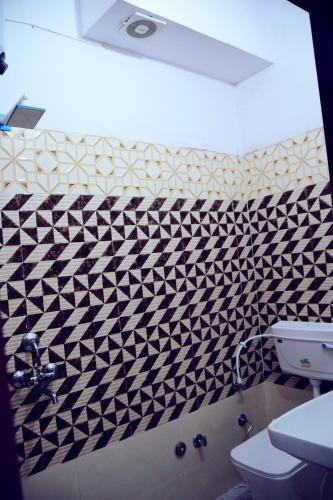 a bathroom with a black and white tiled wall at Hotel Bhatner Inn in Hanumāngarh