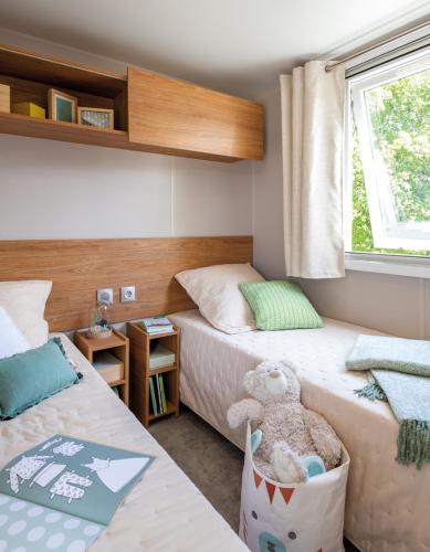 a bedroom with two beds and a stuffed animal in a basket at Camping Le Mas de Reilhe in Crespian