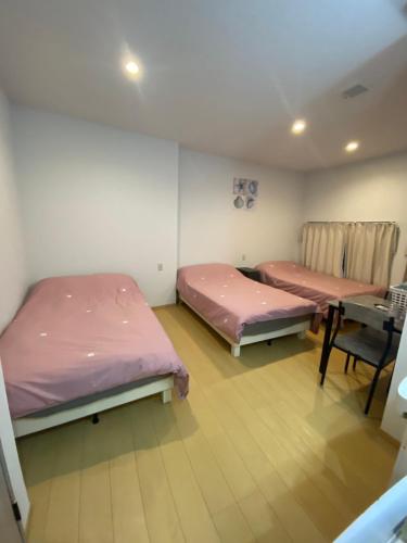 two beds in a room with a table and a desk at Hotel MR TOMO ATAMI 102 in Atami