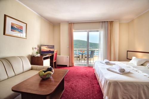 a hotel room with two beds and a couch and a table at Hotel AGAVA in Neum