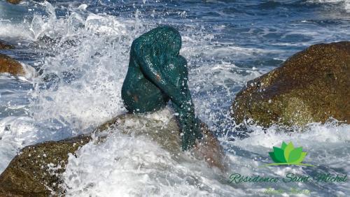 a person in the water on some rocks at Résidence Saint Michel in LʼÎle-Rousse
