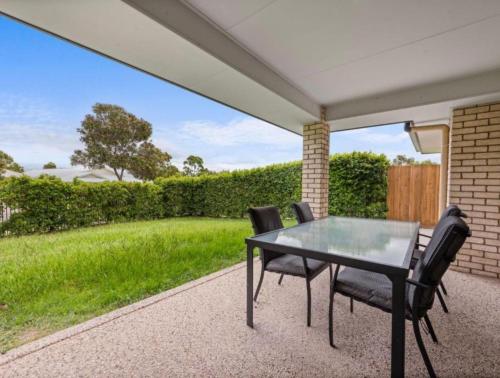 a table and chairs on a patio with a lawn at Riverstone Crescent Residence in Caloundra West